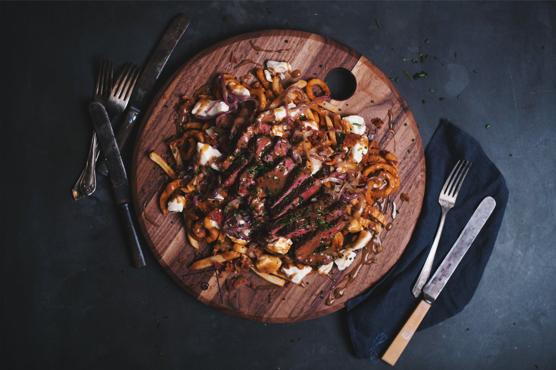 poutine on wooden plate with sliced steak