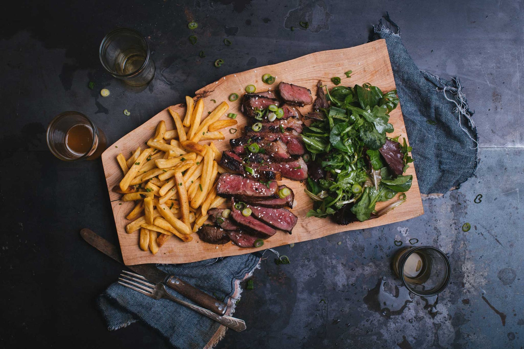sliced medium rare steak, french fries, green salad